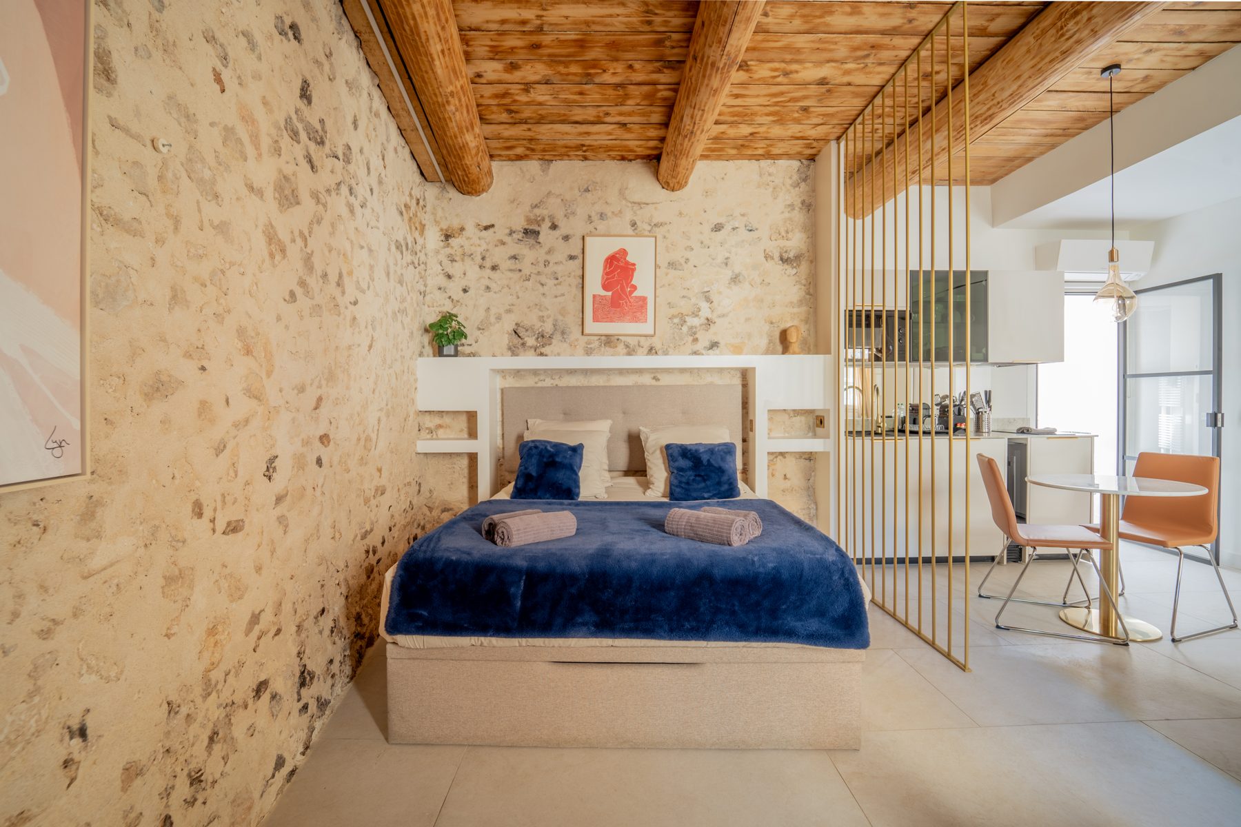 Suite Airbnb sous plafond en bois, murs en pierres apparentes